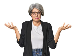 Caucasian mid-age female in business suit doubting and shrugging shoulders in questioning gesture.