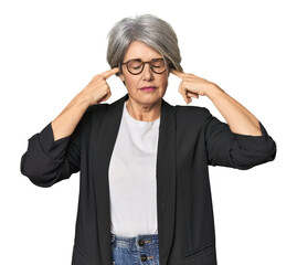 Caucasian mid-age female in business suit covering ears with fingers, stressed and desperate by a...