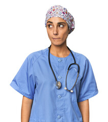 Hispanic nurse in uniform with stethoscope confused, feels doubtful and unsure.