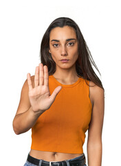 Hispanic young woman standing with outstretched hand showing stop sign, preventing you.