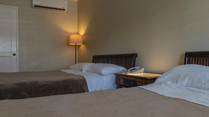 A fragment of the bedroom. Two beds are made with white sheets and brown bedspreads. The pillows...