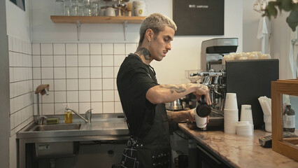Handsome barista guy work coffee shop. Tattooed hipster man. Male face smile. Joy young adult person cafe house. Stylish dyed hair waiter make hot tasty drink order. Latte art cafeteria. Bar staff job
