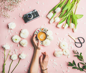 Female hands holding coffee, fresh flowers and film camera