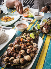 Grilled shells clams served on the table with other staple food in Malaysia.