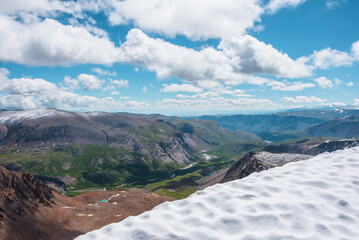 Scenic top view from snowfield on precipice edge to most beautiful alpine valley with long river...