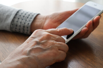 Obraz na płótnie Canvas スマートフォンを操作する高齢女性の手元