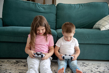 children with joysticks playing video games on the floor at home
