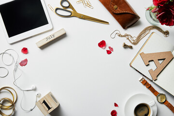 top view of digital tablet, earphones, jewelry, case, flowers, office supplies and coffee on white