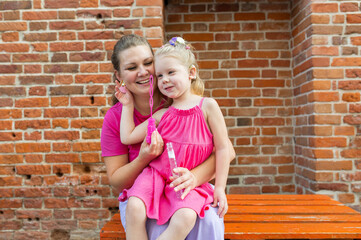 Deaf child with cochlear implant for hearing audio and aid for impairment having fun and laughs with mother outdoor in summer. Sound fitting device to help with communication listening and interaction