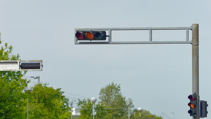 Orange traffic light on a metal pole with a clear blue sky in the background