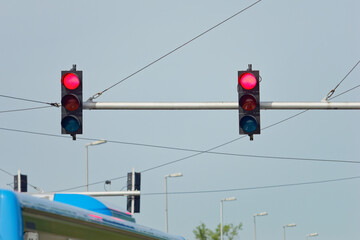 Red traffic lights on a metal pole with a clear blue sky in the background