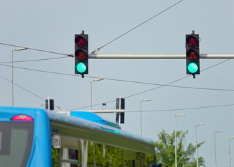 Green traffic lights on a metal pole with a clear blue sky in the background