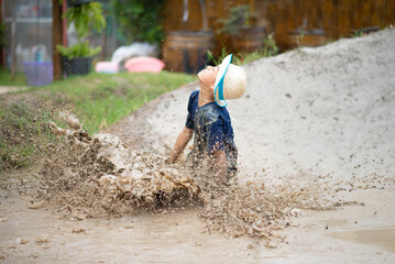 Child enjoys playing in mud pit and sand, embracing nature's playground in all seasons