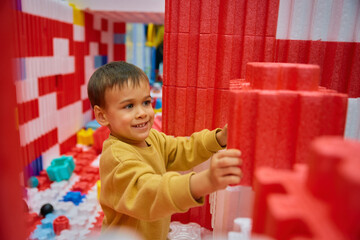 Boy child playing with huge building blocks in entertainment center