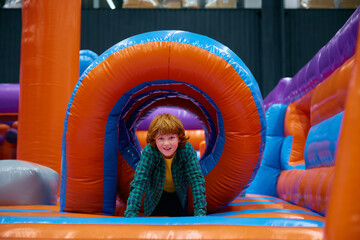 Cute boy playing on inflatable bounce house in entertainment center