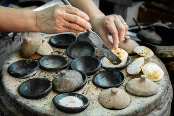 Vietnamese mini fried eggs, with rice flour, street cooking. Woman preparing Traditional Vietnamese breakfast Banh can