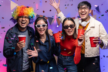 Happy asian diverse group friends celebrating with beer bottles and clinking on party. Home party friends having fun enjoying time and dancing together. New Year's Eve Party concept.
