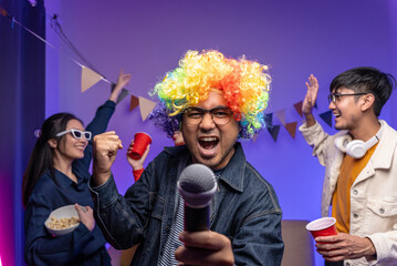 Happy asian diverse group friends singing together on party with neon light. Home party friends...