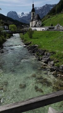 Bavarian Ramsau Berchtesgaden view along a church and icy cold mountain river with the Watzmann mountain chain at the background