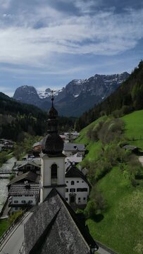 Bavarian Ramsau Berchtesgaden view along a church and icy cold mountain river with the Watzmann mountain chain at the background