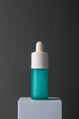 Blue glass cosmetic bottle, Skin care or sunscreen cosmetic on grey background.