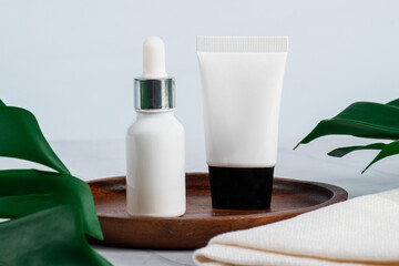 Plastic tube for cream or lotion. Skin care or sunscreen cosmetic with stylish props on tropical monstera leaves background