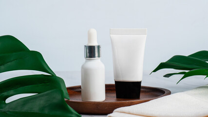 Plastic tube for cream or lotion. Skin care or sunscreen cosmetic with stylish props on tropical monstera leaves background