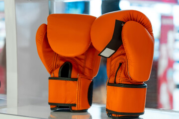 Boxing orange gloves on the shelf of the fightwear shop. Boxing gloves display at sports store....