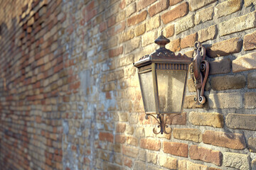 Side view of an Italian outdoor lantern against a textured brick wall highlighting light play.