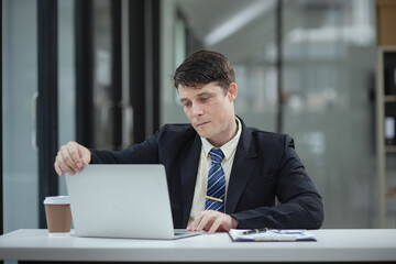 Professional business man trader using laptop computer sitting at office desk in modern office.