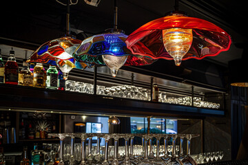 Bar atmosphere under an Italian glass lamp, showing colorful light play on glasses below.