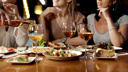 A group of beautiful women talking and having fun together in a restaurant in the evening. A group of girlfriends enjoying food and having fun. Lifestyle concept with happy women on the terrace.