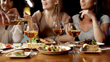 A group of beautiful women talking and having fun together in a restaurant in the evening. A group...
