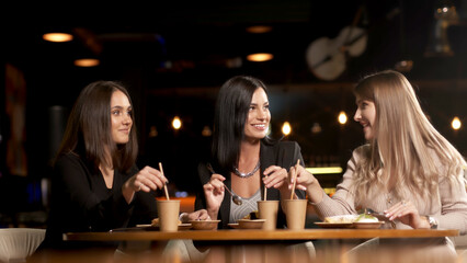Positive girls best friends sitting in a cafe and chatting, colleagues partners gathered in a restaurant during lunch, talking, enjoying conversation, communication, good warm relationship concept