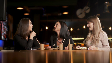 A group of beautiful women talking and having fun together in a restaurant in the evening. A group of girlfriends enjoying food and having fun. Lifestyle concept with happy women on the terrace.