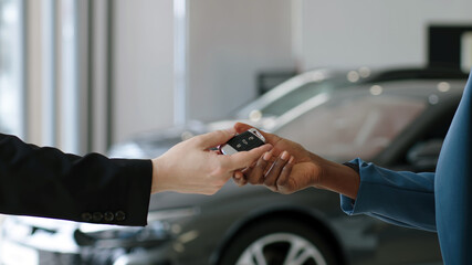 Close-up of the completion of a deal to purchase a new car at a car dealership. The car dealer and...
