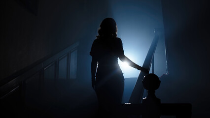 Beauty and form. The silhouette of a beautiful, young woman against a dark background is climbing...
