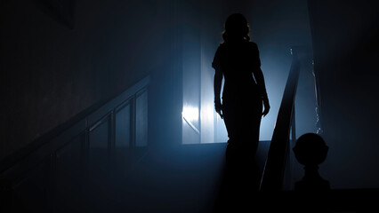 Beauty and form. The silhouette of a beautiful, young woman against a dark background is climbing up the old stairs.