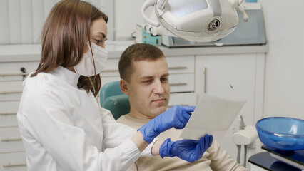 Fototapeta premium A man having a consultation and treatment with a female dentist in a professional dental clinic. Dentistry and dental services.