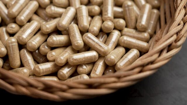 Herbal pills with Fadogia Agrestis plant extract to increase male testosterone and sexual health in eco rattan bowl. Alternative medicine capsules. Rotation