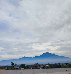 The natural scenery seen from the Indonesian toll road or highway includes mountains, beautiful blue skies, and several cars can be seen