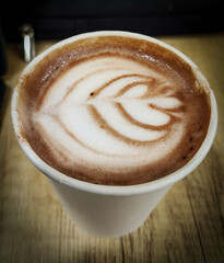 selective focus of an artistically patterned white cup of coffee in a cafe or latte art on the...