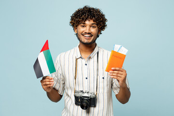 Traveler Indian man wear white casual clothes hold passport ticket, UAE flag isolated on plain blue...