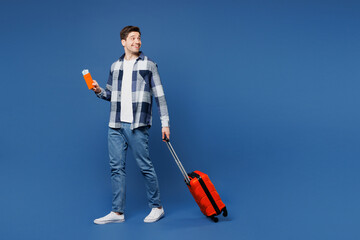 Traveler man wears shirt casual clothes hold bag passport ticket look aside isolated on plain blue background. Tourist travel abroad in free spare time rest getaway. Air flight trip journey concept.