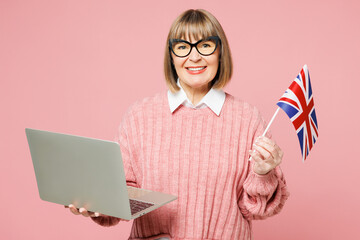 Elderly IT woman 50s years old wear sweater shirt casual clothes glasses hold British flag use work...