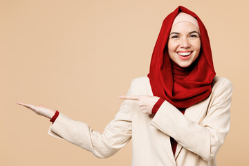 Young fun Arabian Asian Muslim woman wear red abaya hijab suit clothes point index finger aside on...