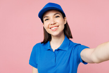 Close up professional delivery girl employee woman wear blue cap t-shirt uniform workwear work as dealer courier do selfie shot on mobile cell phone isolated on plain pink background. Service concept