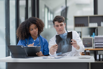 female African American doctor and doctor man working with examining x-ray reports at hospital.