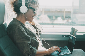 Young woman work on laptop with headset sitting on bus seat. Travel business lifestyle female...