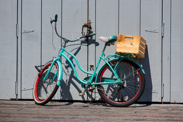 Colorful old bike with mint frame and red rims leaning locked on grey wooden door in bright...
